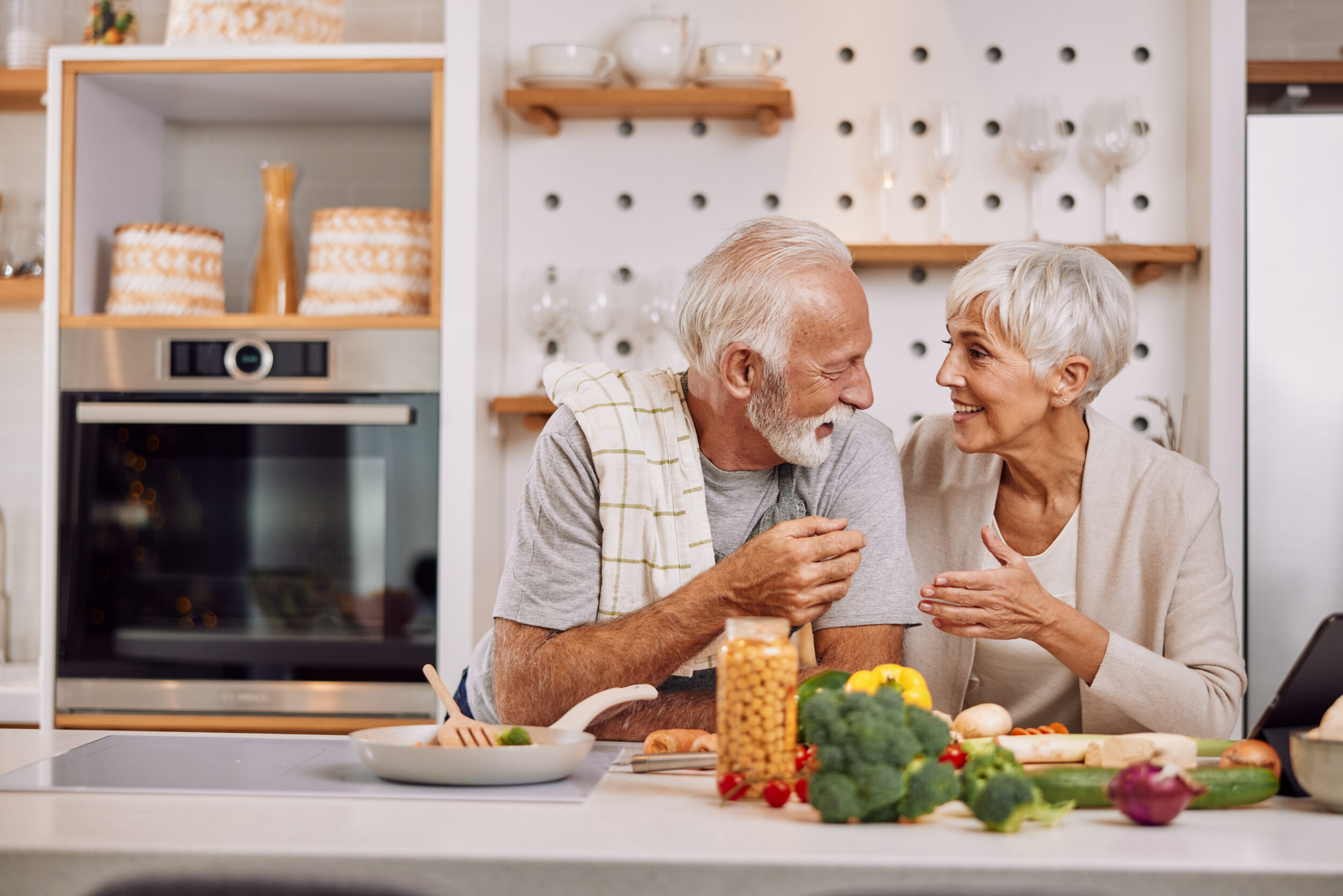 a happy senior couple preparing a healthy meal together, using a tablet