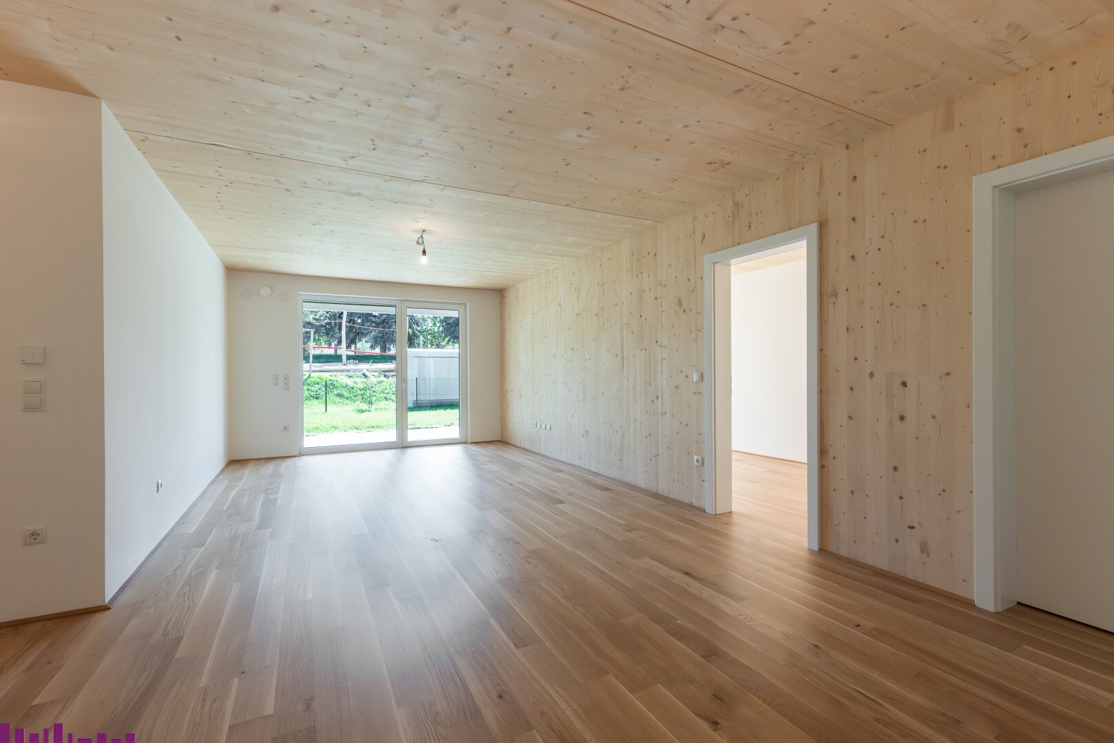 Zimmer der Eigentumswohnung mit Sichtholzdecke und Holzboden