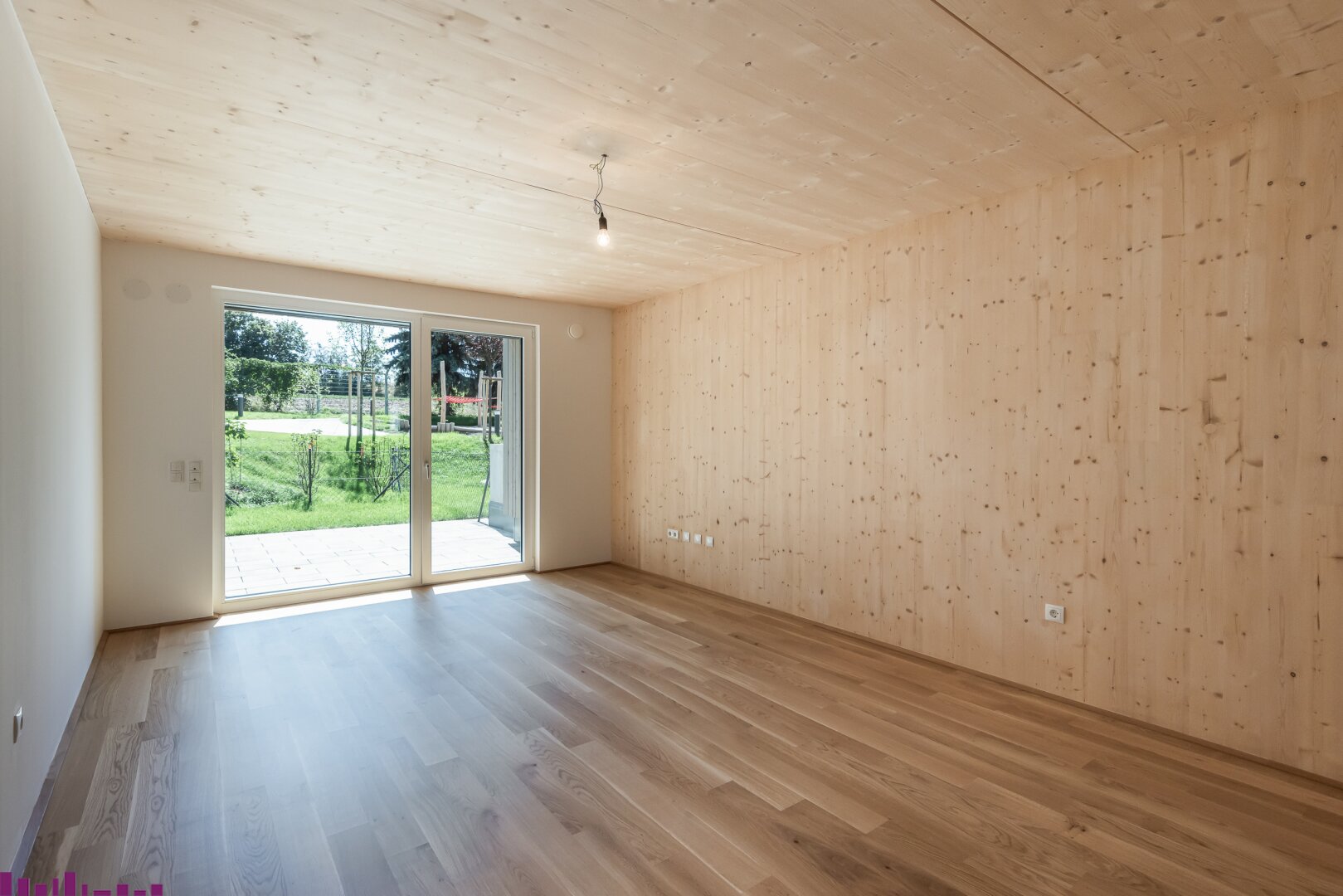 Zimmer der Eigentumswohnung mit Sichtholzdecke und Holzboden